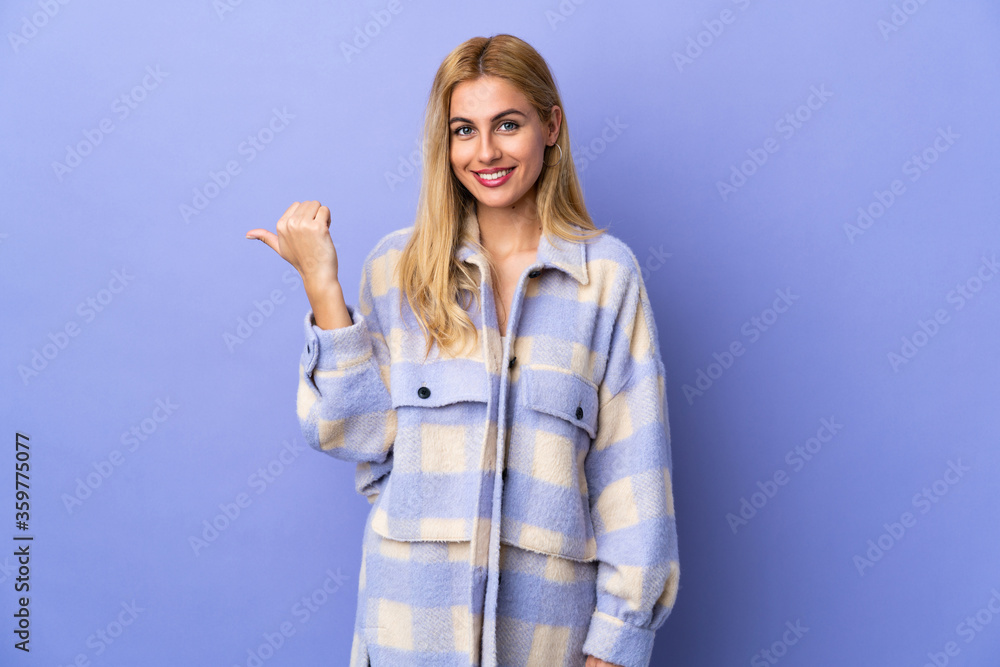 Fototapeta premium Young Uruguayan blonde woman over isolated background pointing to the side to present a product