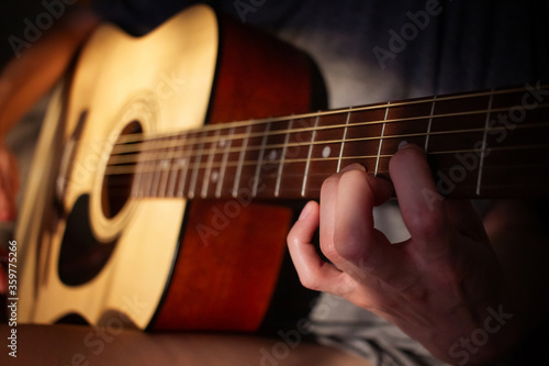 Close up photo of a girl plays the guitar at home. Warm evening sunlight and yellow tones. self-development at home