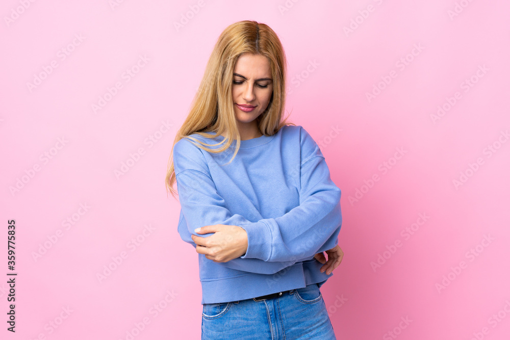 Young Uruguayan blonde woman over isolated pink background with pain in elbow Young Uruguayan blonde woman over isolated pink background with pain in elbow