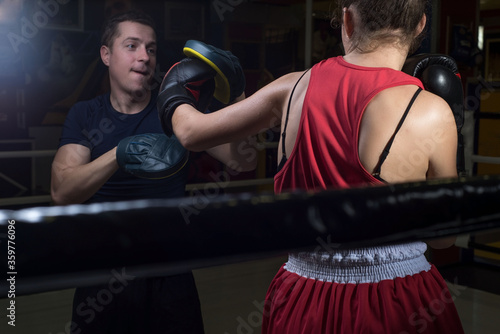 Portrait of a boxing trainer guy training a young athlete training her in martial arts. In a boxing club. Girls learn self-defense, martial art.