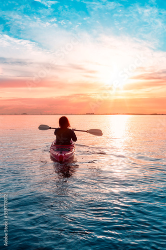 Sea Kayaking in calm waters during a colorful and vibrant sunset. Adventure Girl in Red Kayak. Location  White Rock  Vancouver  British Columbia  Canada.