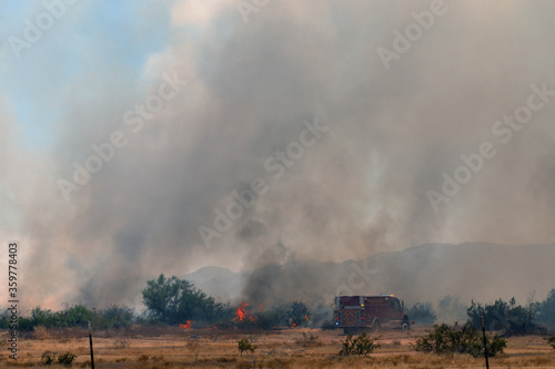 Raging Arizona arson wildfire in rural area with firefighters battling pillars of smoke and flame