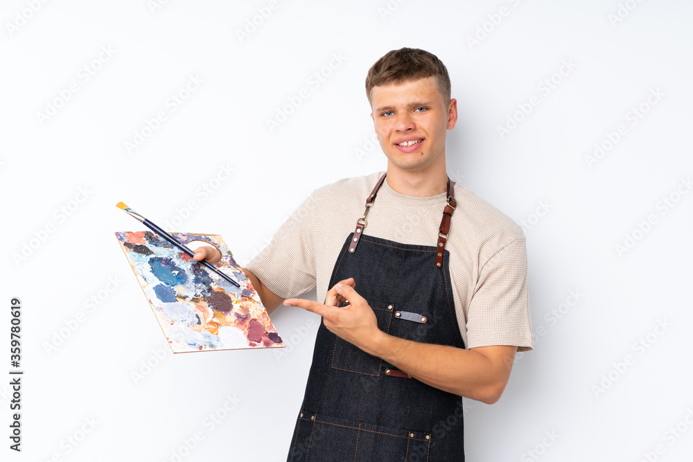 Young handsome man over isolated white background holding a palette and pointing it Young handsome man over isolated white background holding a palette and pointing it