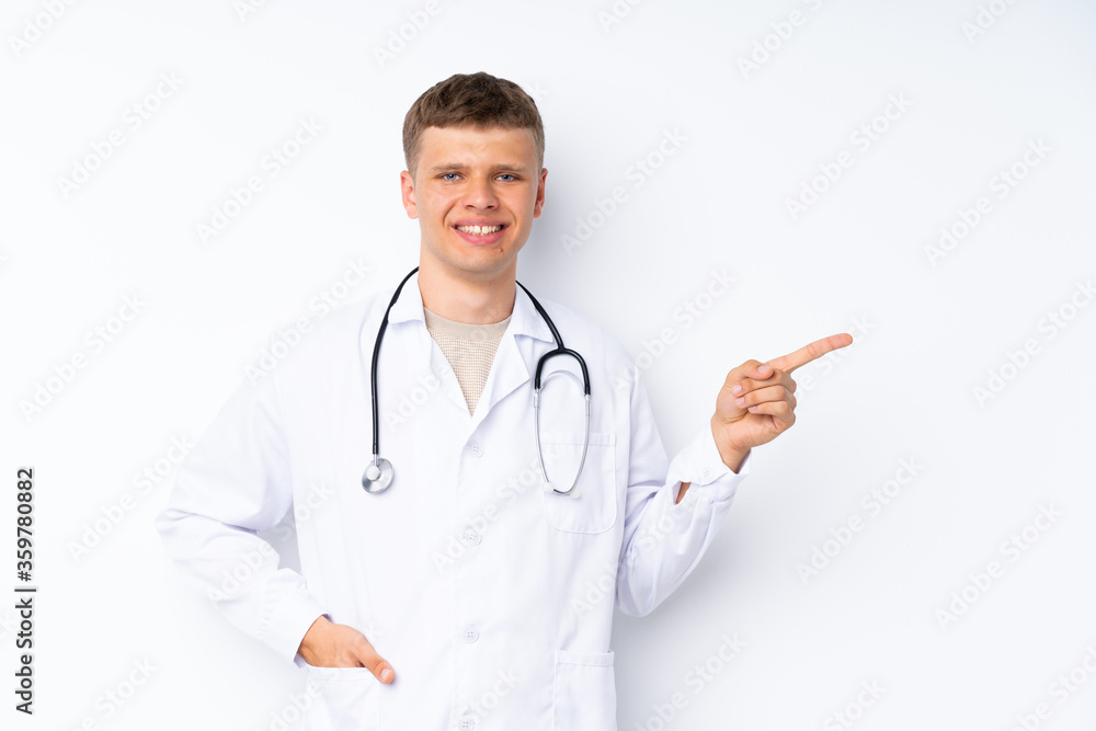 Young handsome man over isolated white background with doctor gown and pointing side Young handsome man over isolated white background with doctor gown and pointing side