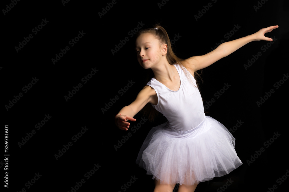 Cute little girl in a tutu and pointe shoes is dancing in the studio on a black background. Cute little girl in a tutu and pointe shoes is dancing in the studio on a black background.