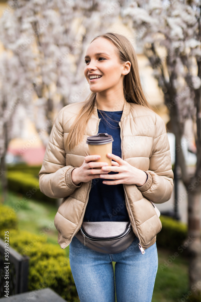 Young pretty girl near a blossoming tree with a cup of coffee on the spring tree Young pretty girl near a blossoming tree with a cup of coffee on the spring tree