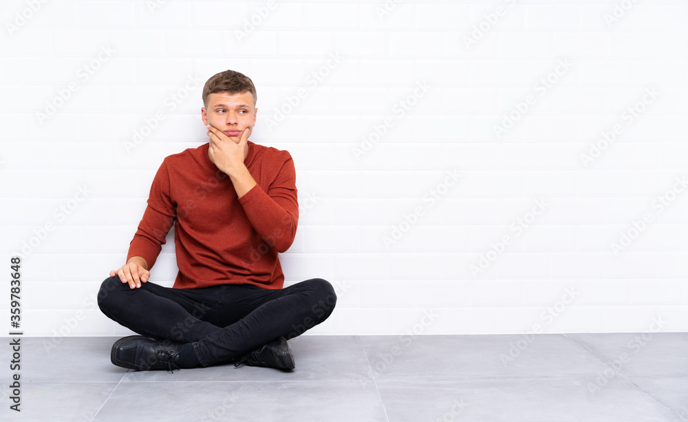 Young handsome man sitting on the floor thinking an idea Young handsome man sitting on the floor thinking an idea