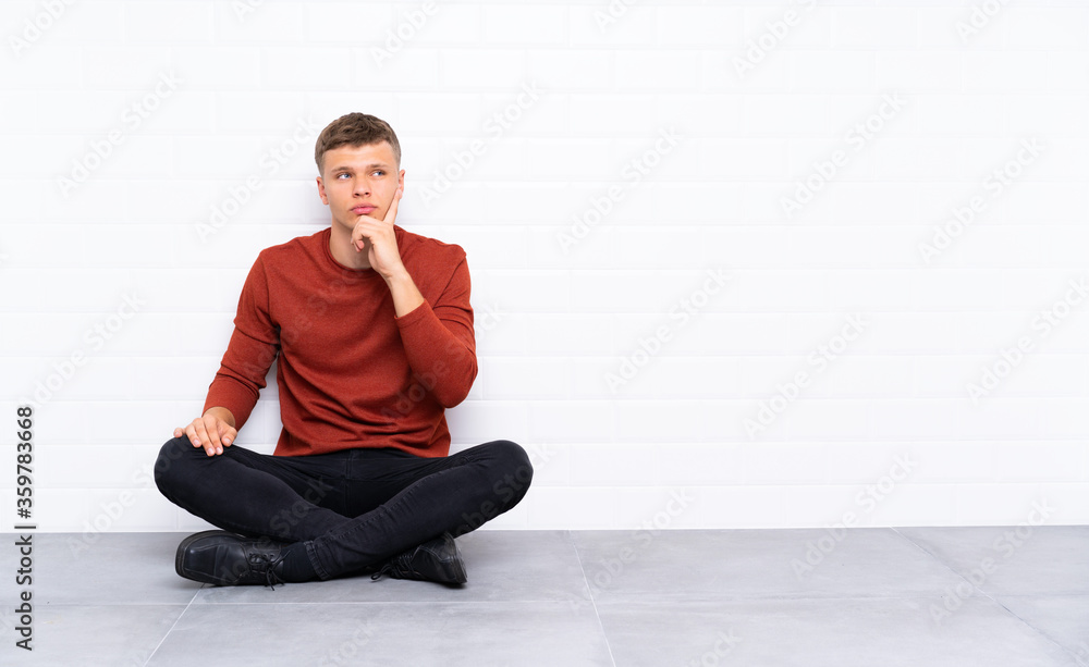 Young handsome man sitting on the floor thinking an idea Young handsome man sitting on the floor thinking an idea