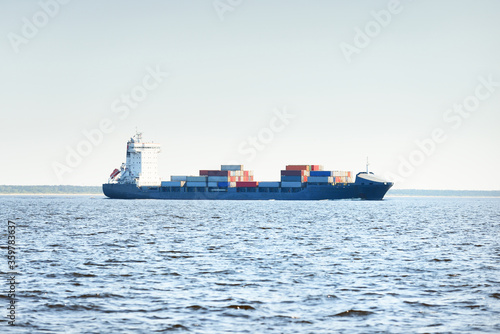 Large cargo container ship sailing from Europoort (Rotterdam, Netherlands) on a clear day, close-up. Freight transportation, global communications, logistics, environmental damage theme photo