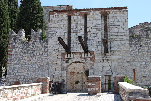 Stone wall with merlons and drawbridge gate of medieval castle of Brescia in north Italy photo