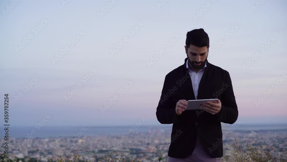 Businessman using tablet and working with sunset skyline in background Businessman using tablet and working with sunset skyline in background