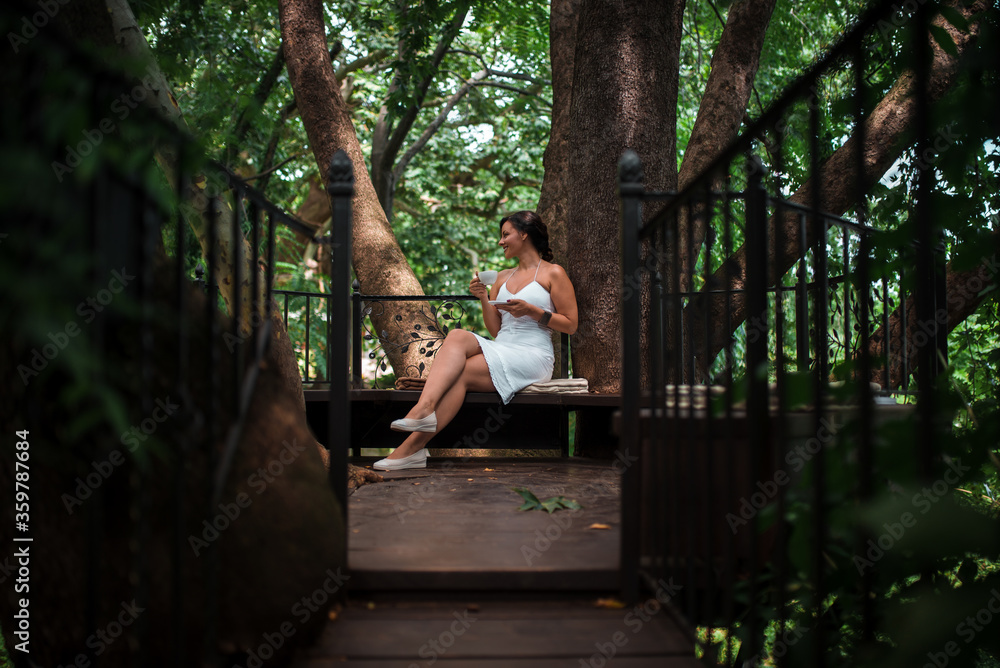Lady drinking coffee in majestic wooden treehouse balcony cafe. Lady drinking coffee in majestic wooden treehouse balcony cafe.