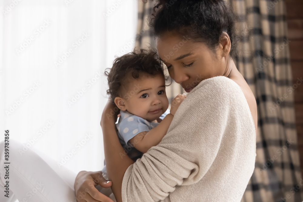 Close up loving African American young mother holding adorable toddler daughter, cuddling, family enjoying tender moment together, caring mum hugging cute little girl with closed eyes, childcare Close up loving African American young mother holding adorable toddler daughter, cuddling, family enjoying tender moment together, caring mum hugging cute little girl with closed eyes, childcare