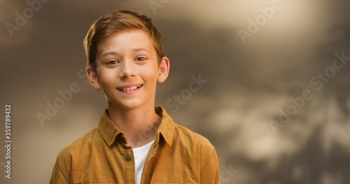 Portrait shot of Caucasian teen cute small boy looking at camera and smiling cheerfully. Close up of face of little teenage smiled schoolboy. photo