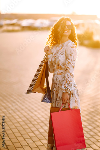 Woman in shopping. Young Girl with colorful shopping bags walking around the city after shopping. Consumerism, purchases, shopping, lifestyle concept.