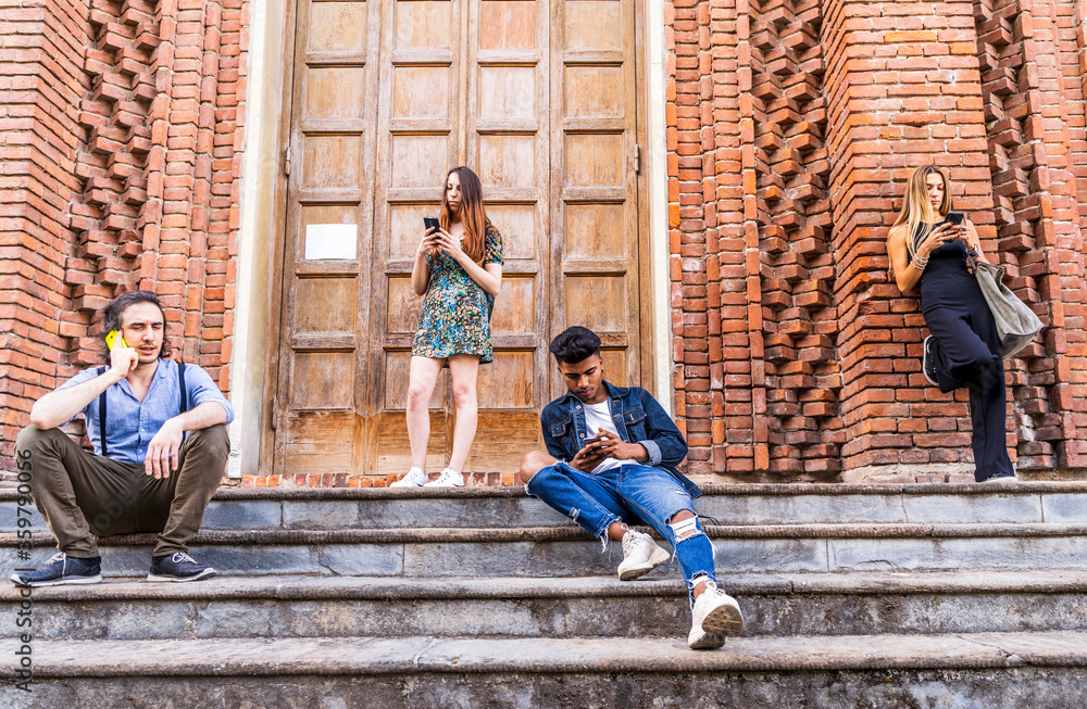 group of multiracial friends sitting on a marble staircase using smartphones