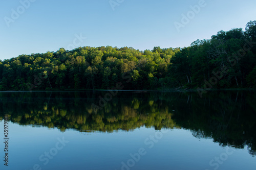Calm lake surrounded by trees at sunset