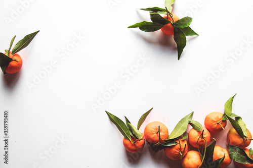 Oranges fruits composition with green leaves on white wooden background, top view