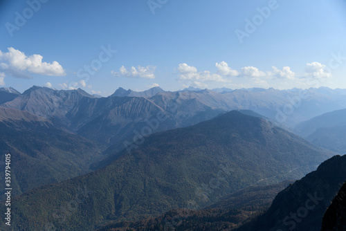nature landscape and travel concept - mountains and trees against the blue sky in early autumn
