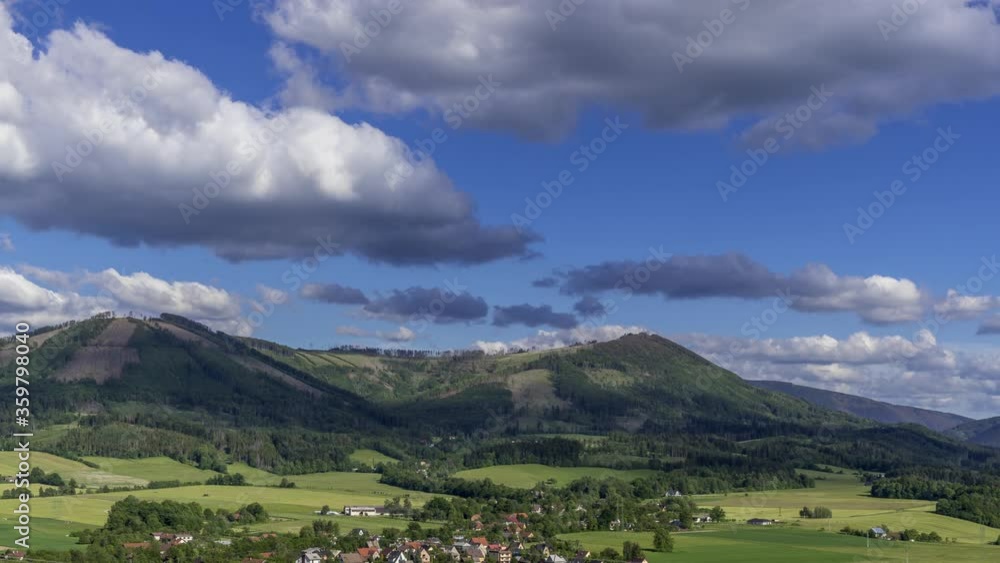 Timelapse to the tops of Ondrejnik mountains with the village of Kozlovice lying below the mountain with clouds moving over hills and shadows projecting changing the forest landscape by reflection. Timelapse to the tops of Ondrejnik mountains with the village of Kozlovice lying below the mountain with clouds moving over hills and shadows projecting changing the forest landscape by reflection.