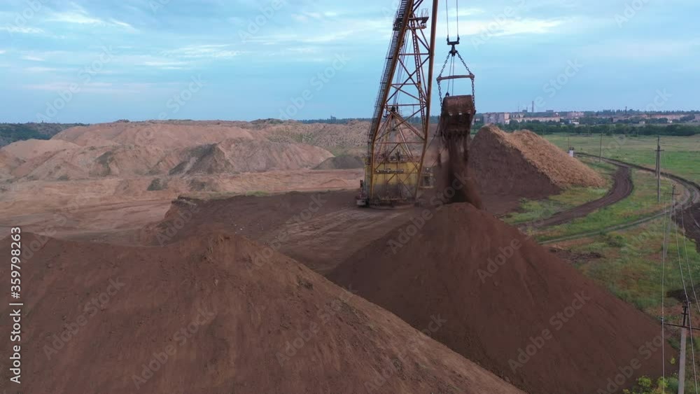 A large old quarry excavator removes the top layer of soil at the site of mining. Aerial view. A large old quarry excavator removes the top layer of soil at the site of mining. Aerial view.
