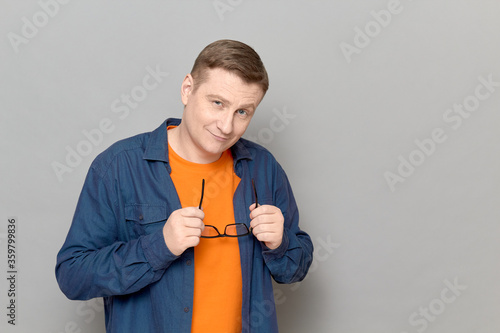 Foto Portrait of friendly mature man holding glasses in hands and smiling