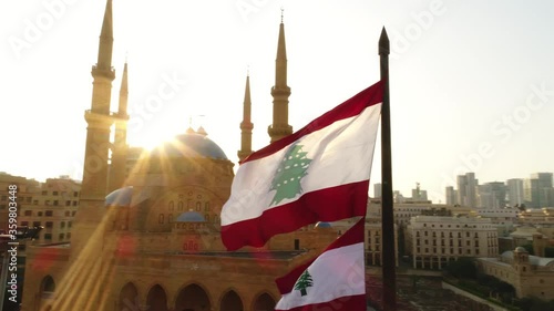 Beirut, Lebanon 2019: sunset turn around drone shot on Lebanese flag with mosque, church and sun flaring in the background during the Lebanese revolution photo