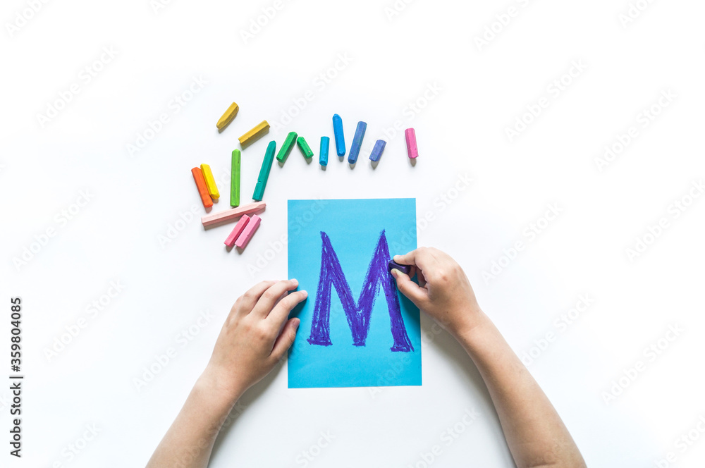 Children's hands write the letter M chalk Children's hands write the letter M chalk
