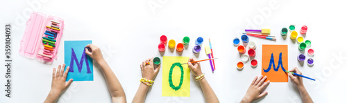 Children's hands write the word Mom