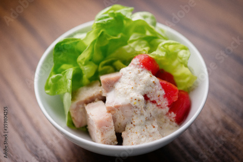 roasted chicken or pork salad with tomato, lettuce with creamy dressing in a white bowl