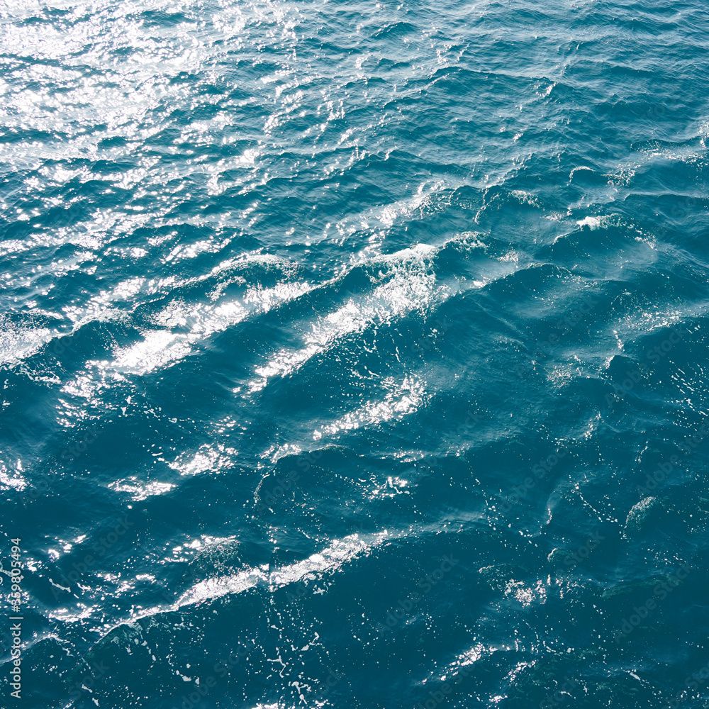 Sea water, natural texture of ocean water, blue sea, glimmers of the sun on the waves, view from the ship to the ocean