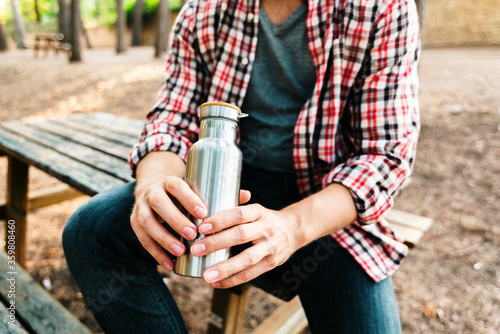 Aluminum bottle for water in the hands of a young man.