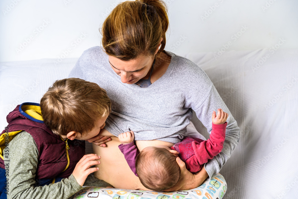 Mom breastfeeding her two sons in tandem, the two brothers share her mom's breast.