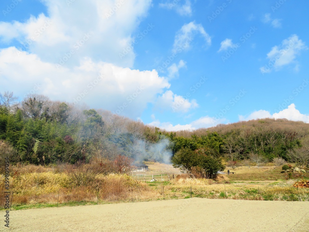 日本の田舎の風景 2月 早春の畑焼き 山の木々と青空 Stock-Foto 