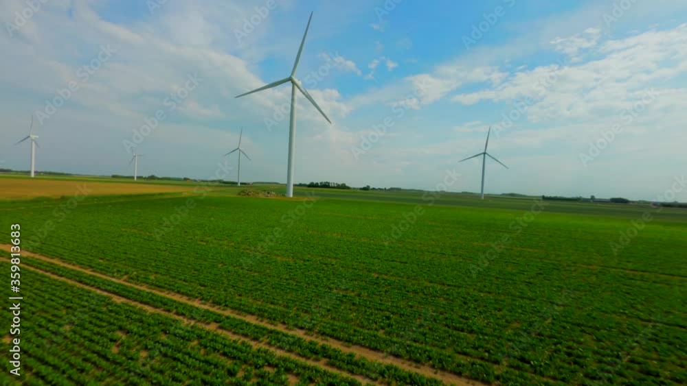 Aerial drone flight above potato farm with tall rotating wind turbines Aerial drone flight above potato farm with tall rotating wind turbines