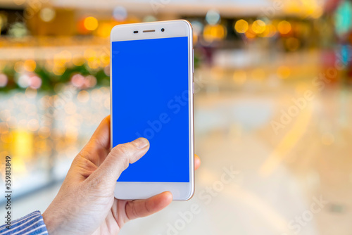 Hand holding smart phone with abstract blur in shopping mall background