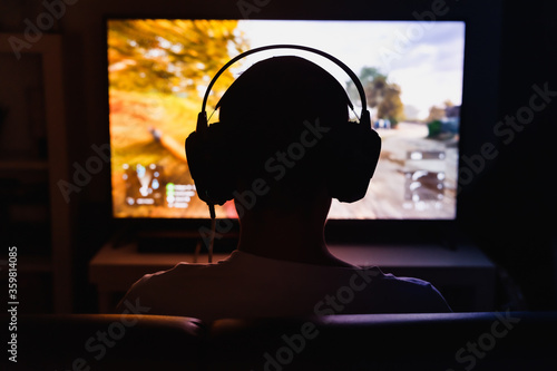 Men wearing headphones playing video games at night.