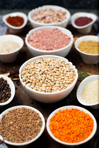 Red lentils, wheat, rice and buckwheat in a white bowl on a wooden board