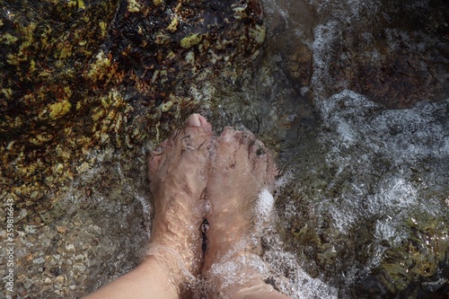 Relaxing mind and body by soak my feet in the clear water of the sea with surrounded by sand  gravel  stone and sea shells which feels great.