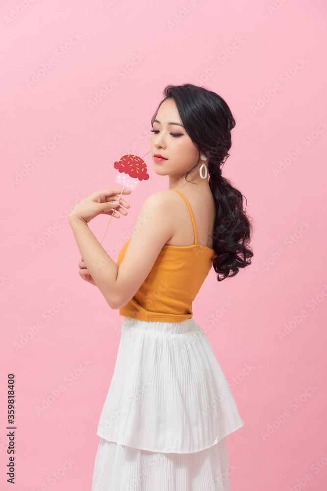 Pink background happy woman holding cakes make from paper on a stick Pink background happy woman holding cakes make from paper on a stick