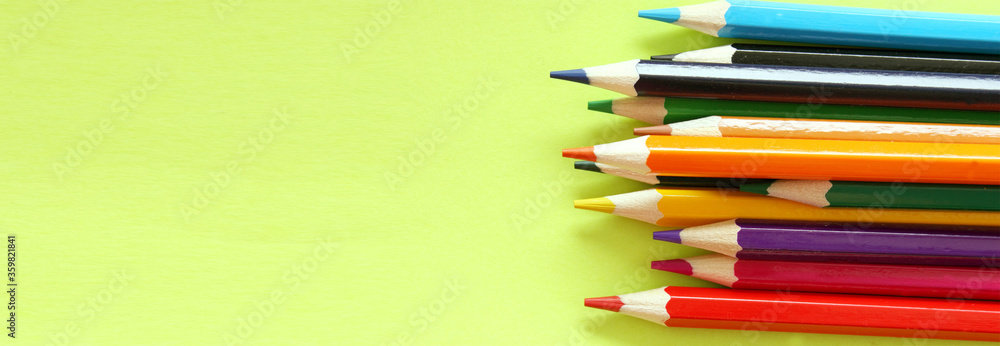 Colored pencils on a yellow background. Lots of different colored pencils. Colored pencil. Pencils are sharp. Pencils are on the right. Close-up. Copy space. Background. Banner Colored pencils on a yellow background. Lots of different colored pencils. Colored pencil. Pencils are sharp. Pencils are on the right. Close-up. Copy space. Background. Banner