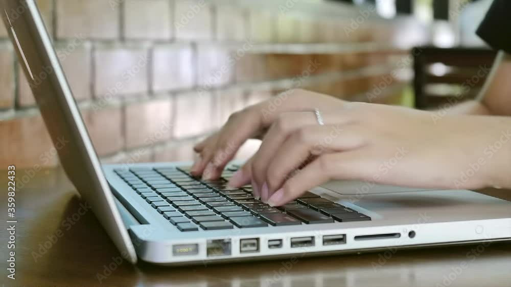 Close-up of a women hands typing on a laptop keyboard over the wooden desk busy working Close-up of a women hands typing on a laptop keyboard over the wooden desk busy working