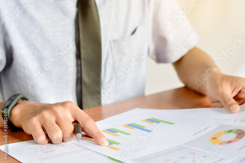 Businessman analyze graph report on table and holding the pen and analyzing the graph