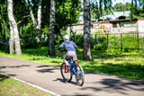 boy rides a bicycle on a park path, rear view
