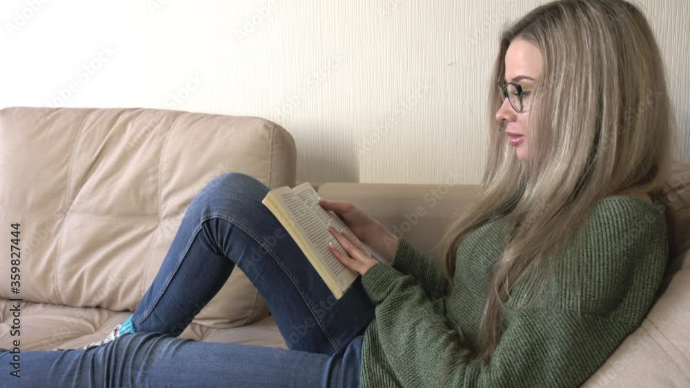 A pretty young woman is happy to read a book at home