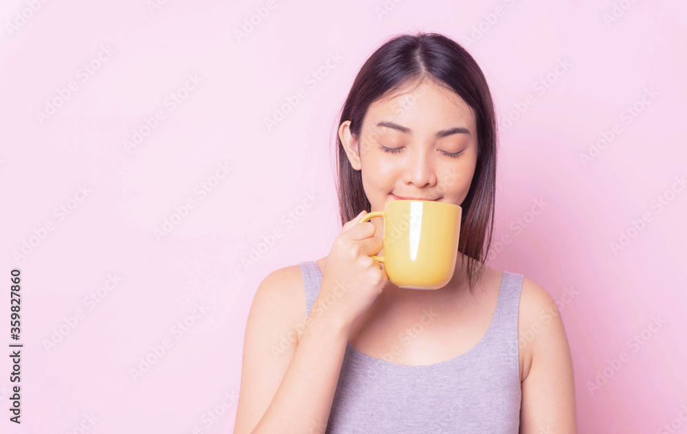 Healthy woman smile and drink morning coffee from yellow ceramic mug in morning breakfast,young asian girl isolated portrait pink color background ,copy space Healthy woman smile and drink morning coffee from yellow ceramic mug in morning breakfast,young asian girl isolated portrait pink color background ,copy space