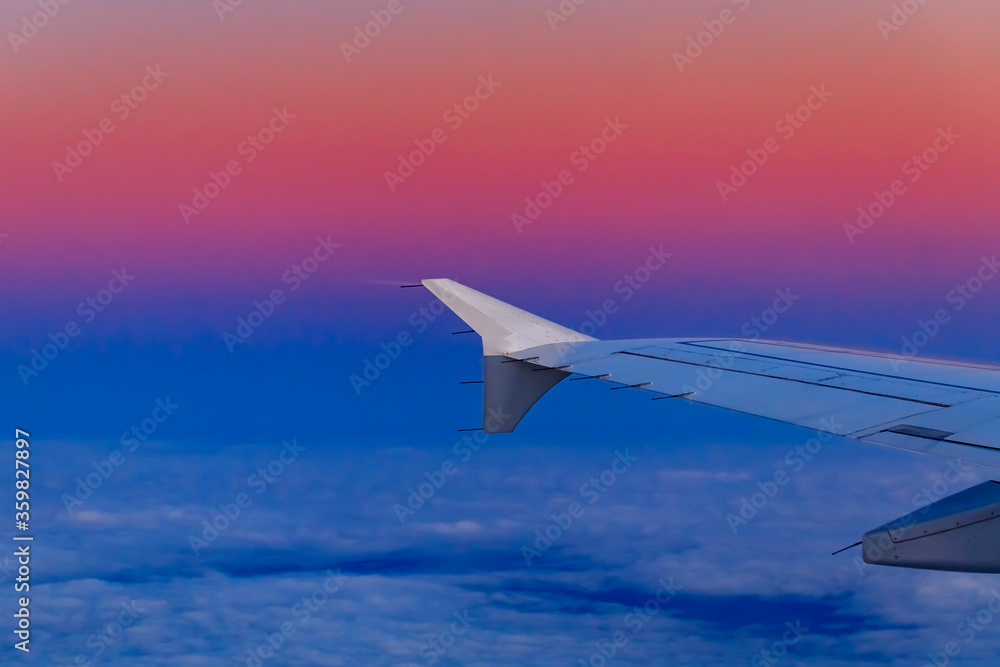 Colorful fluffy clouds and airplane wing from an airplane at sunset Colorful fluffy clouds and airplane wing from an airplane at sunset