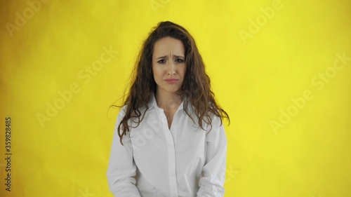 Displeased, frustrated and sad young woman on yellow background