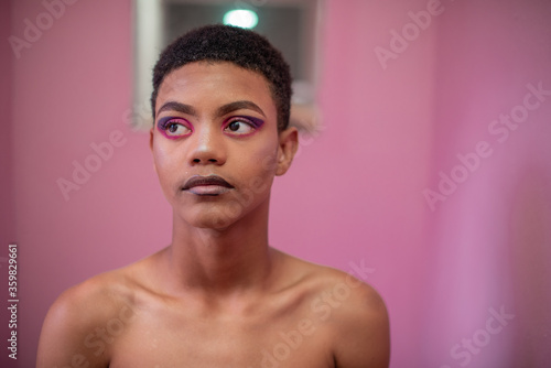 Portrait of young queer male in room with pink wall