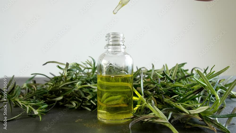 Dripping of fresh rosemary oil into bottle on table Dripping of fresh rosemary oil into bottle on table